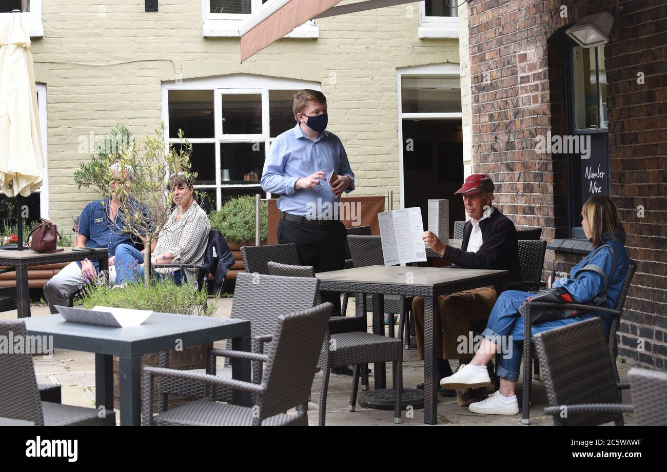 Ironbridge torna alla vita mentre pub, ristoranti e negozi riaprono durante il fine settimana. Un membro del personale del White Hart indossa una maschera facciale che prende o Foto Stock