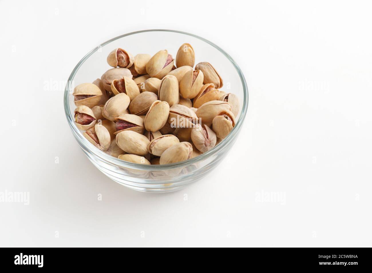 Spuntino con birra. Piccola lastra di vetro con pistacchi isolati su sfondo bianco Foto Stock