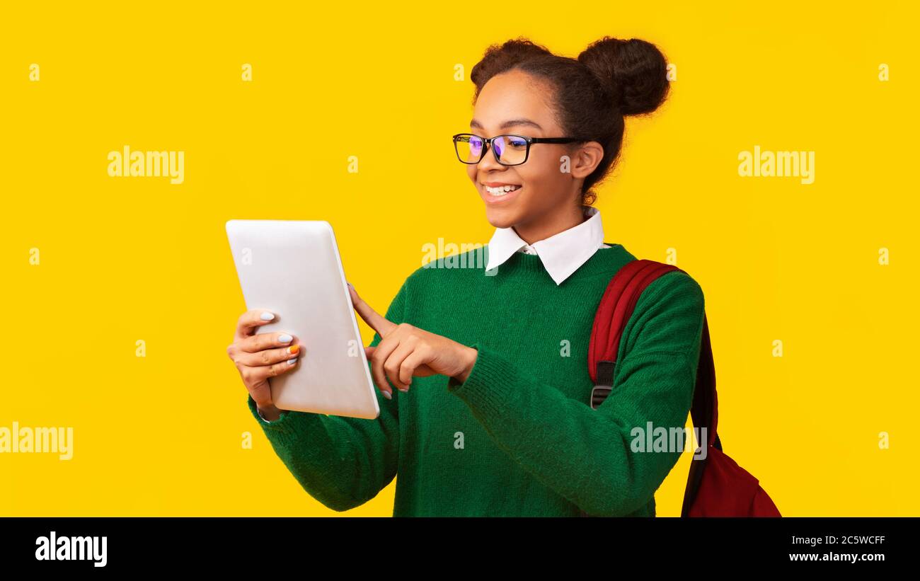 Sorridente ragazza nera in piedi con tablet in studio Foto Stock