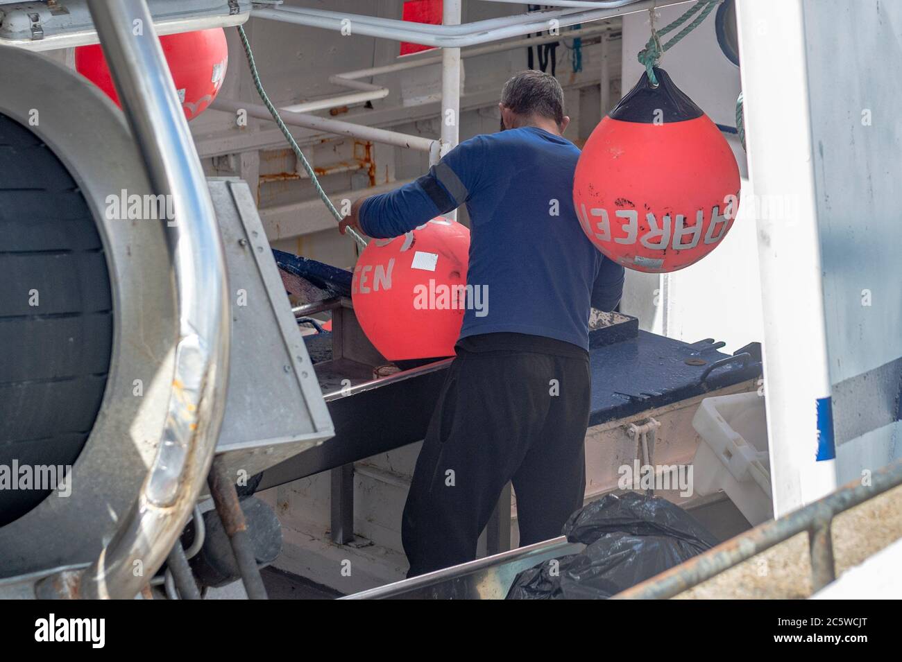 Union Hall, West Cork, Irlanda. 5 luglio 2020. Un pescatore lavora su boe sul suo peschereccio da traino "Caareen", mentre ormeggiato in Union Hall Fishing Harbour. Il porto era pieno di pescherecci da traino ormeggiati che si rifugiavano a causa dei venti di forza delle balle. Credit: Notizie dal vivo di AG/Alamy Foto Stock