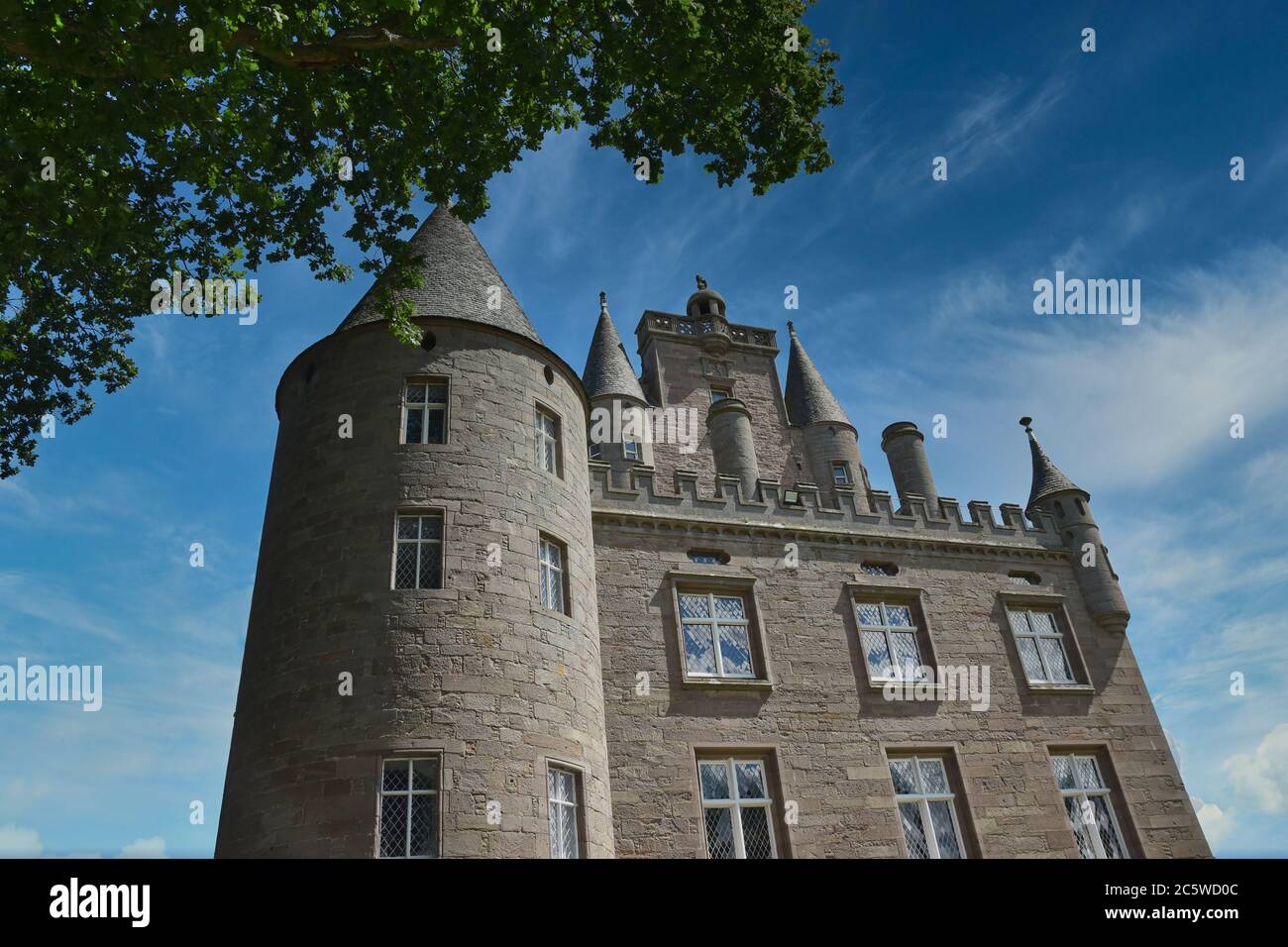 Esterno del Castello di Glamis in Scozia con finestre e torrette,  incorniciate da foglie di alberi, con cielo blu e nuvole di luce in  giornata di sole Foto stock - Alamy