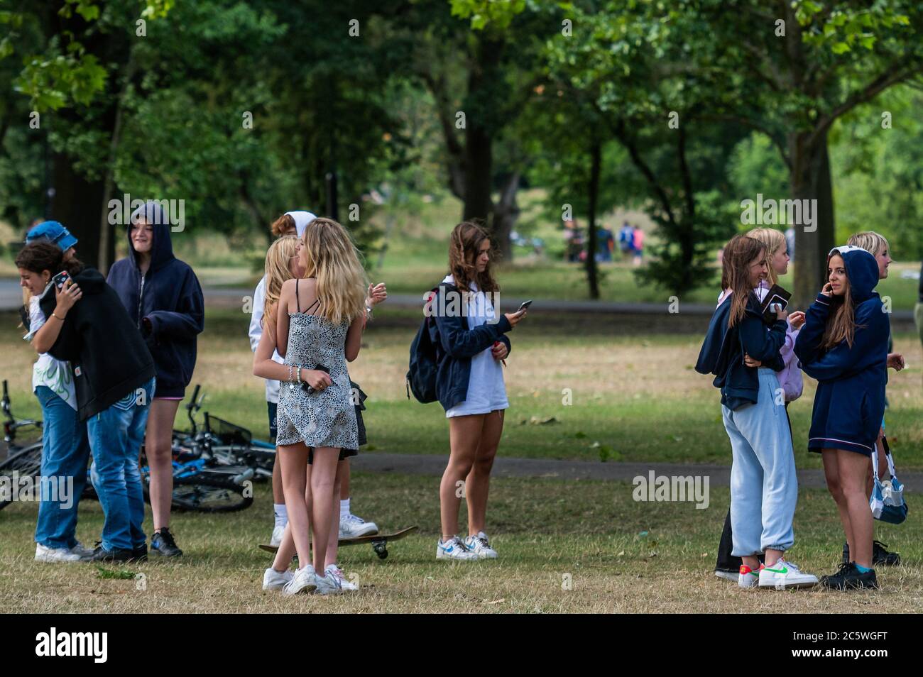 Londra, Regno Unito. 05 luglio 2020. Un gruppo di adolescenti ignora il clapping e tutte le altre regole di divaricamento sociale come essi superano i numeri di guida, abbraccio e non fare alcun tentativo di distanza sociale - Clap per i nostri caregivers, sembra dimenticato su Wandsworth comune come vita bere, Avere gelati e rilassarsi al sole continua quasi sempre a essere immutato intorno alle 5 - questo dovrebbe essere un ringraziamento speciale per NHS e altri lavoratori chiave e caregivers. Il "blocco" dei morti continua a Londra - l'epidemia di Coronavirus (Covid 19) a Londra. Credit: Guy Bell/Alamy Live News Foto Stock