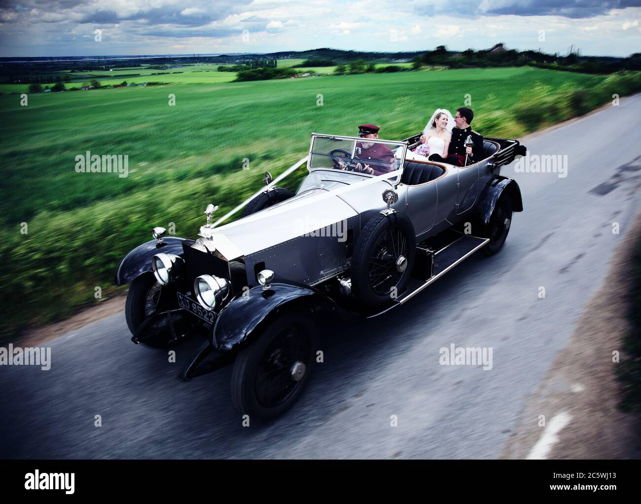 Raro veicolo classico vintage Rolls Royce Silver Ghost in movimento degli anni '20. Sposa e sposo guidati da un autista il giorno del loro matrimonio. Foto Stock