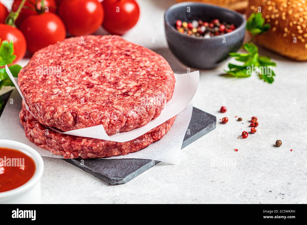 Polpettine di hamburger crudo sulla tavola, sfondo bianco. Foto Stock