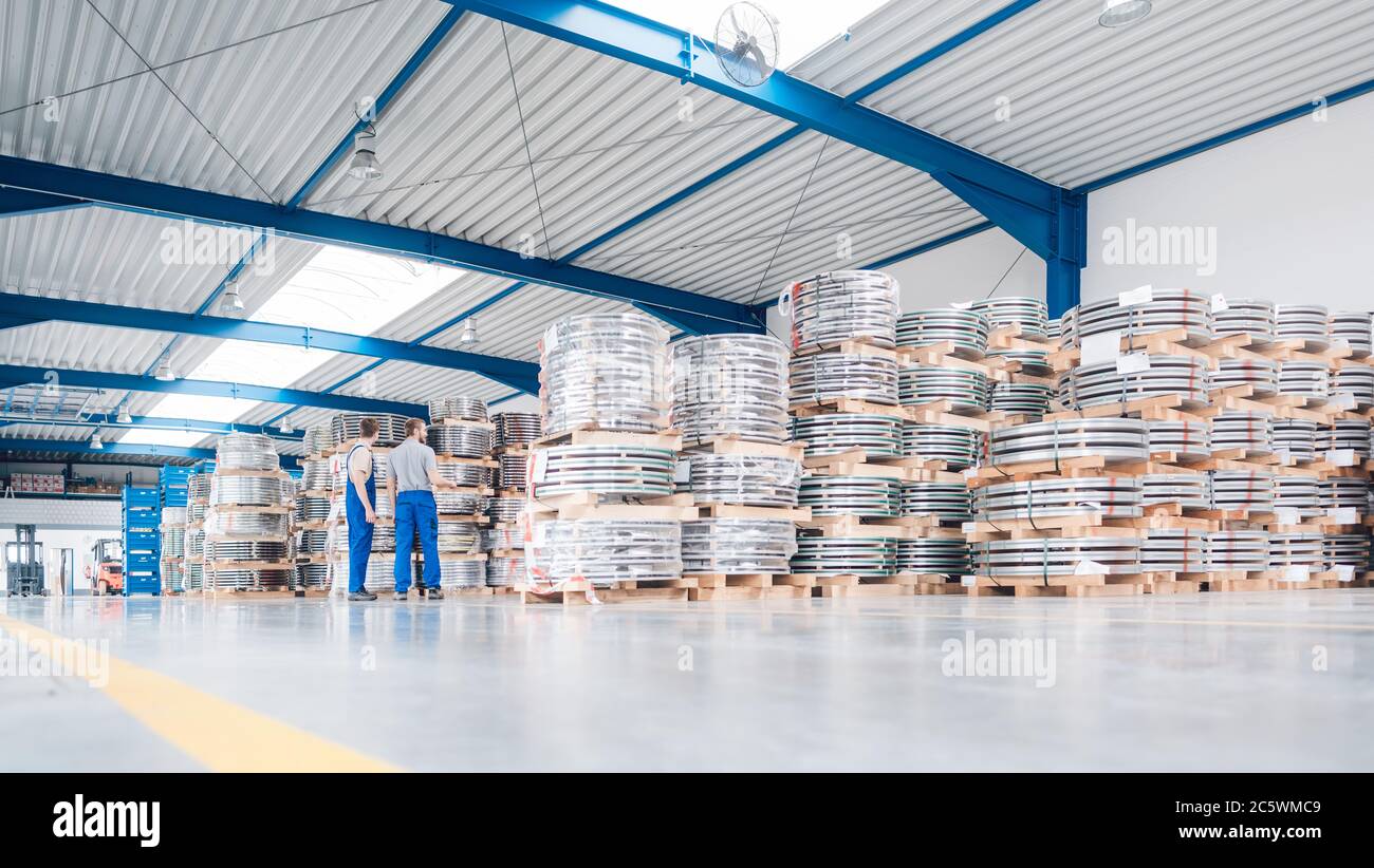 Lavoratori che cercano materiali industriali nell'inventario del magazzino Foto Stock
