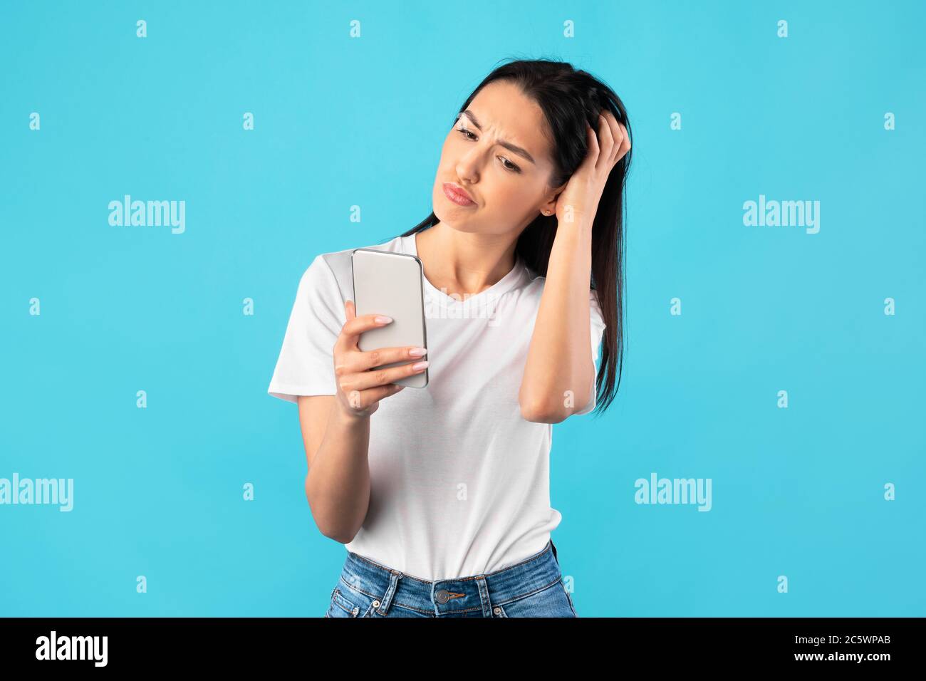 Giovane bella donna confusa con il telefono cellulare Foto Stock