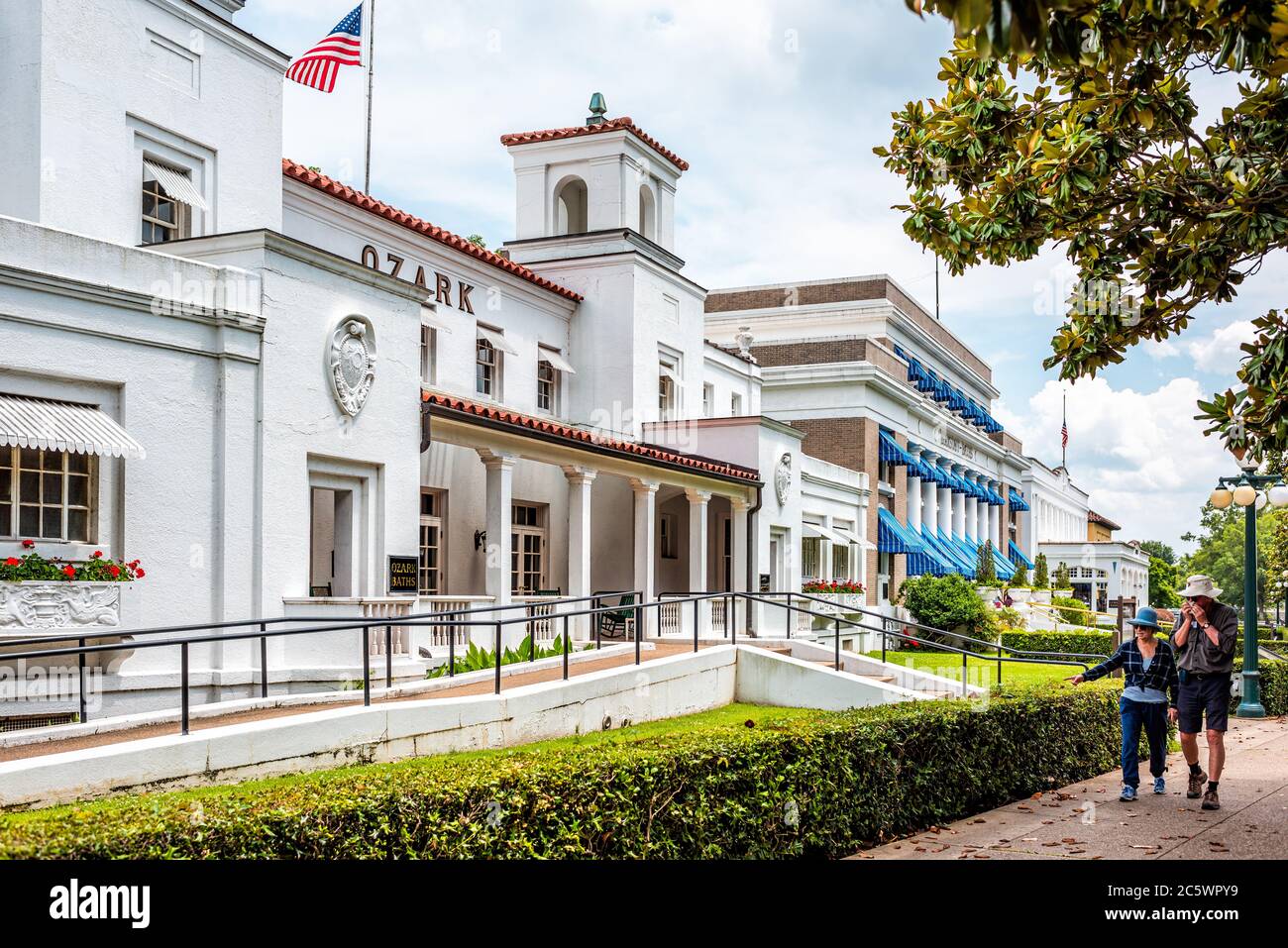 Hot Springs, USA - 4 giugno 2019: Storico bagni termali Ozark Spa architettura bianca bagno casa con bandiera americana e cupola di magnolia albero meridionale in cit Foto Stock