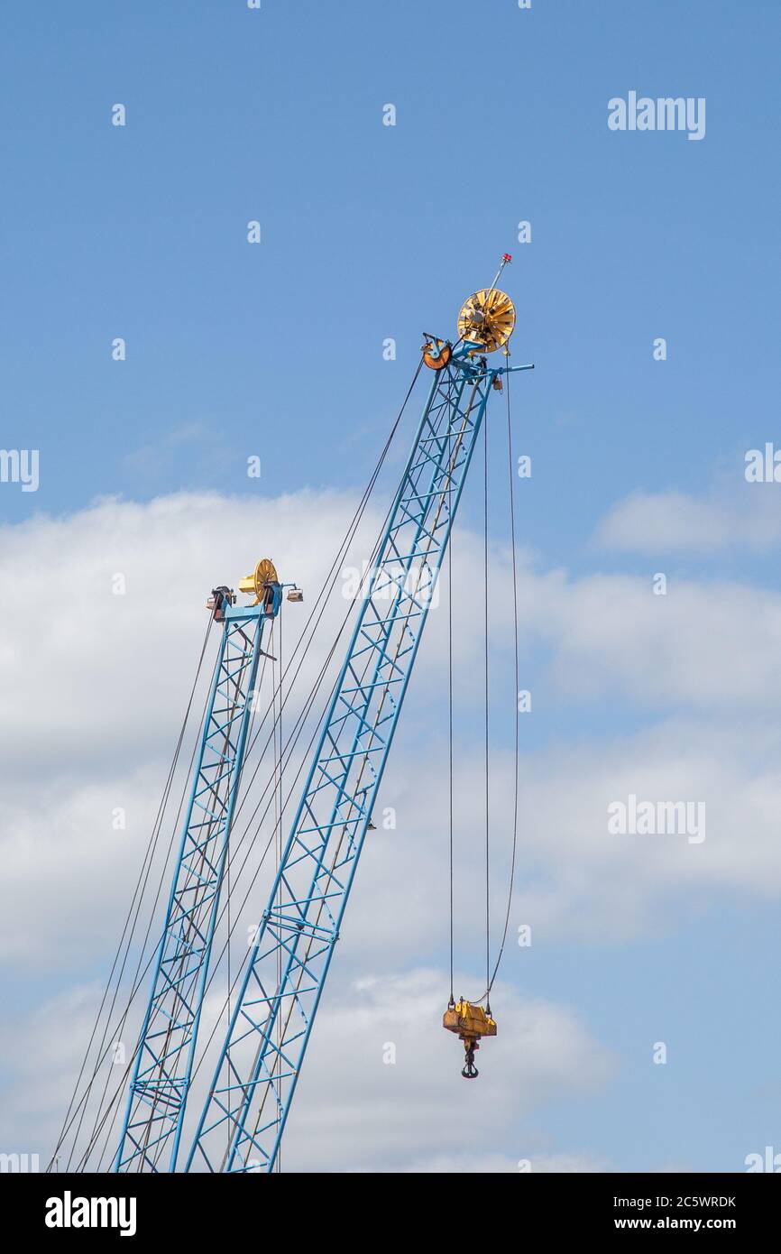due gru metalliche utilizzate su un molo su un cielo blu Foto Stock