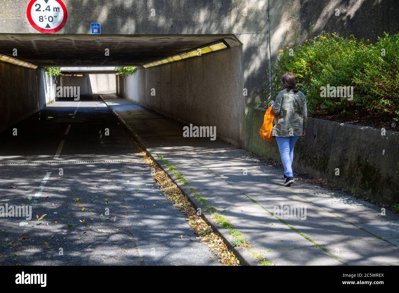 Una donna che cammina da sola per camminare sotto una metropolitana o un passaggio sotterraneo Foto Stock