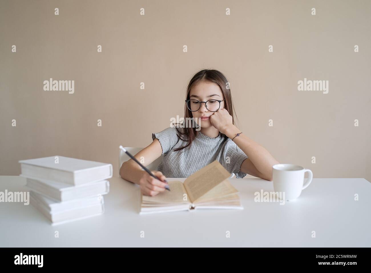 Ragazza adolescente carina seduta a tavola con libri e facendo compiti. Istruzione, bambini e concetto scolastico Foto Stock