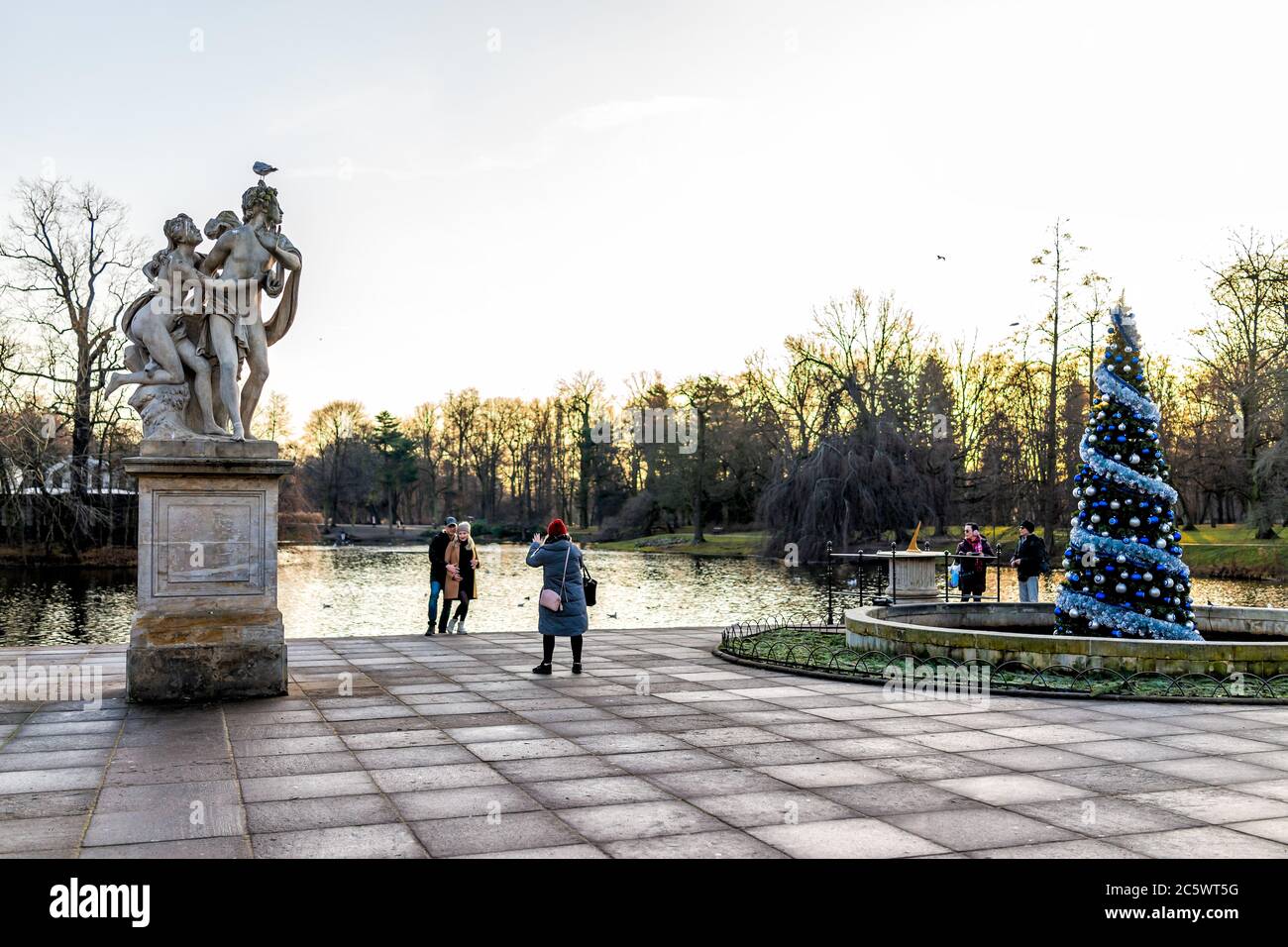 Varsavia, Polonia - 20 dicembre 2019: Persone che scattano foto di alberi di Natale decorati e del lago canale a Warszawa Lazienki o Royal Baths Park Foto Stock