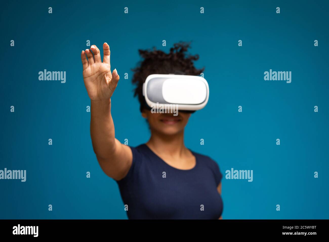 Donna nera nel visore VR premendo il pulsante sullo schermo virtuale Foto Stock