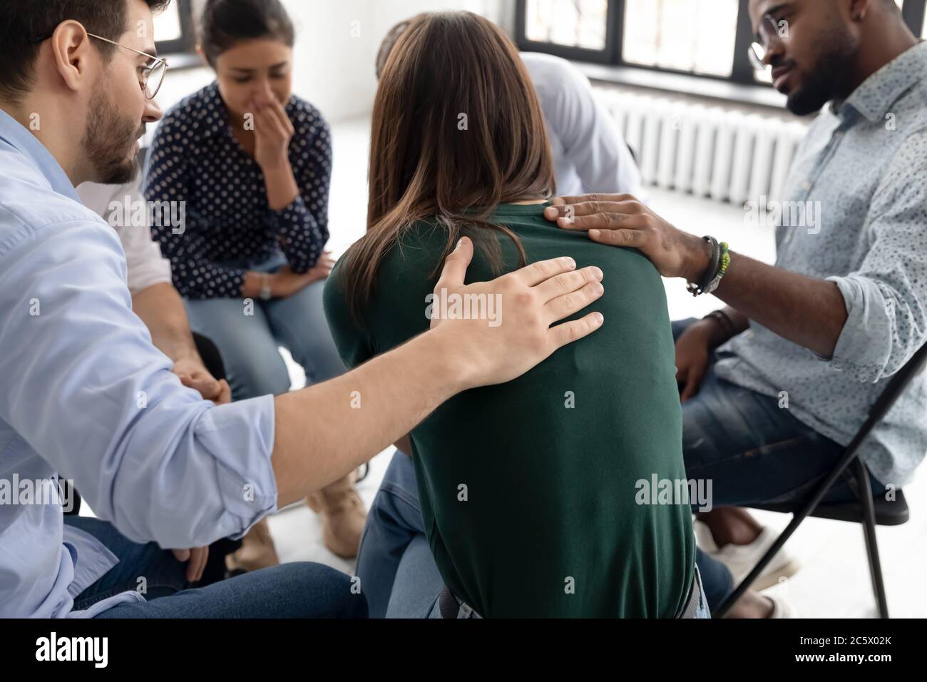 Durante la sessione di terapia di gruppo membri che sostengono piangendo ragazza disperata Foto Stock