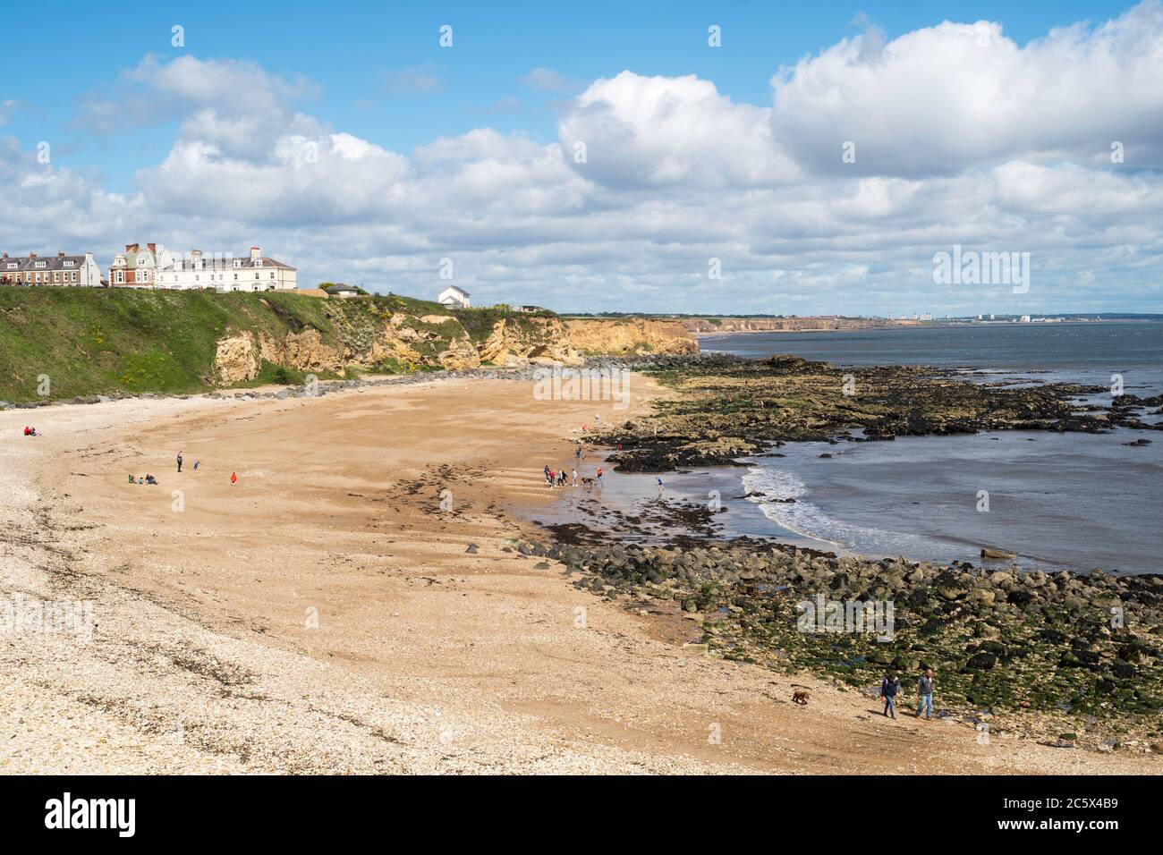 La gente gode del sole di luglio, nonostante i venti forti, sulla spiaggia di Red Acre, Seaham, Co. Durham, Inghilterra, UK Foto Stock