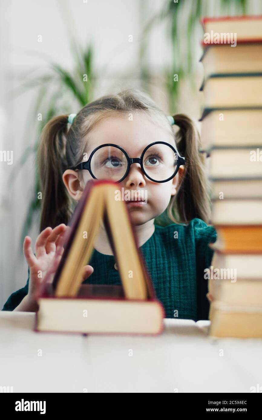 Forma triangolare a un libro in piedi su un altro. Bambina in bicchieri rotondi su sfondo. Istruzione primaria Foto Stock