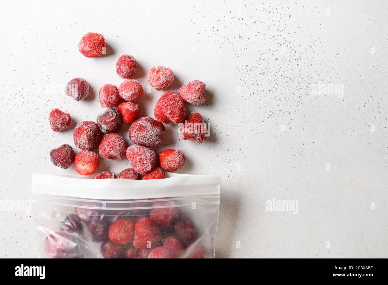 Fragole congelate in confezione di plastica su bianco. Vista dall'alto. Foto Stock