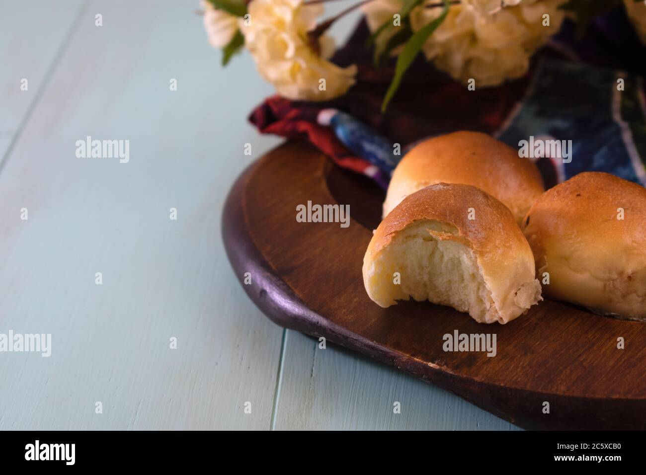 Piccole grappoli di pane su piastra di legno su rustico aqua menthe di legno sfondo colorato con spazio di copia Foto Stock
