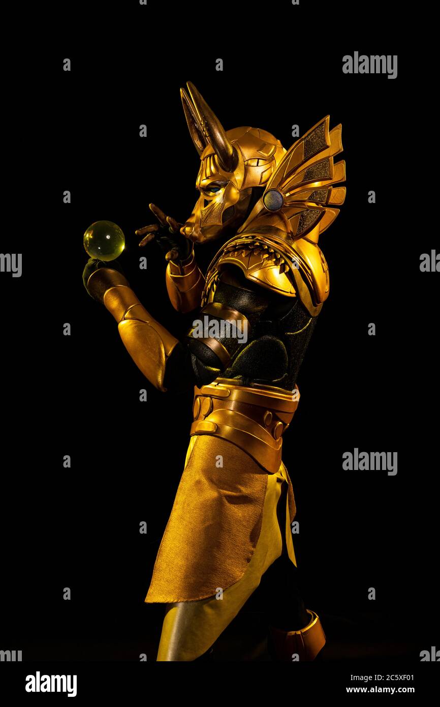 Un attore maschio in un vestito di un personaggio mitologico egiziano, la  divinità d'oro Jackal Anubis, torce buugeng in luce gialla su uno sfondo  nero Foto stock - Alamy