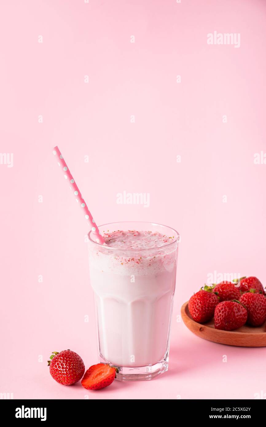 Frullato di latte fresco con fragole su sfondo rosa. Bevanda detox estiva. Posiziona per il testo. Foto Stock