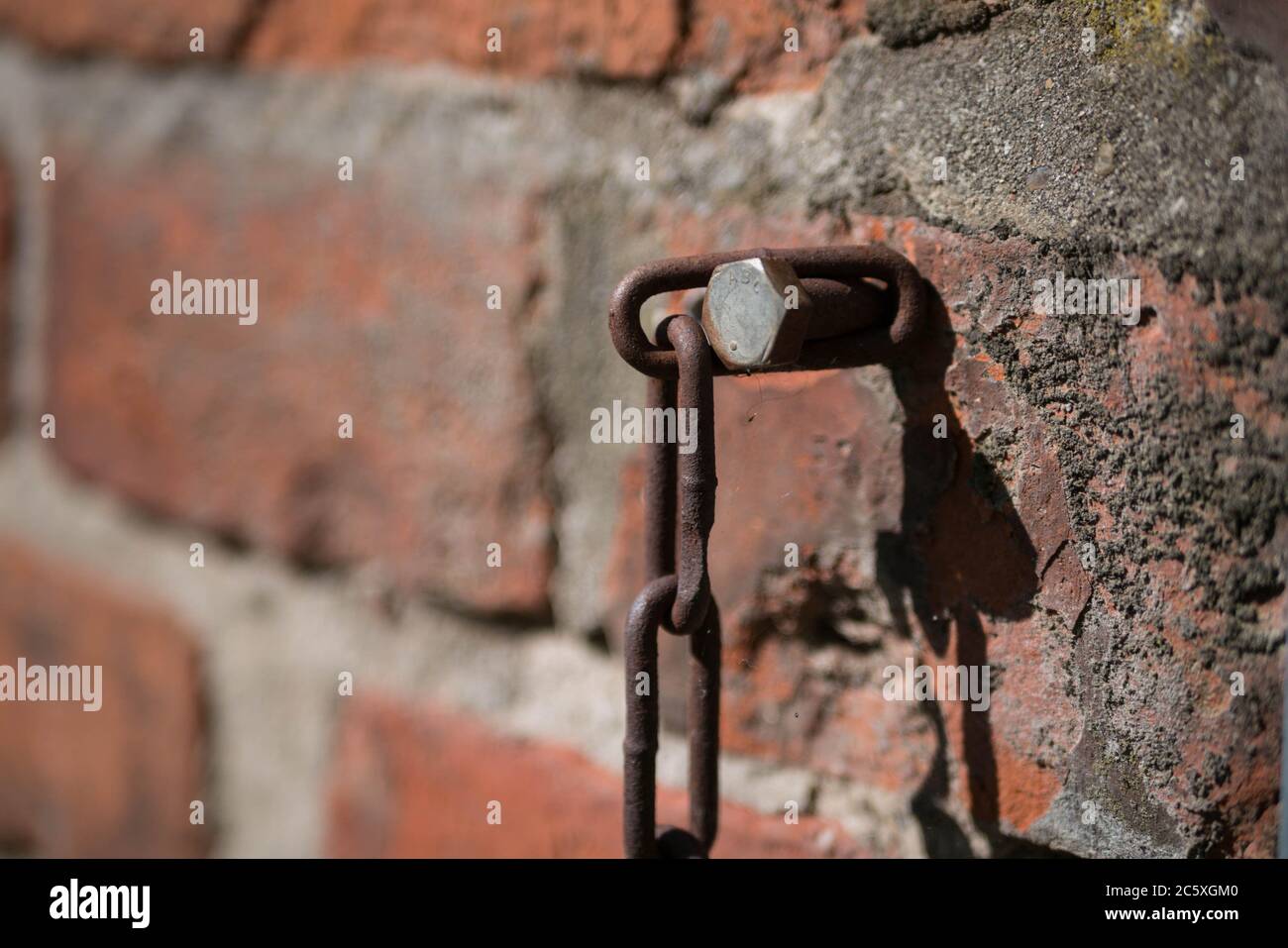 Avvitare con catena arrugginita in una parete di mattoni Foto Stock