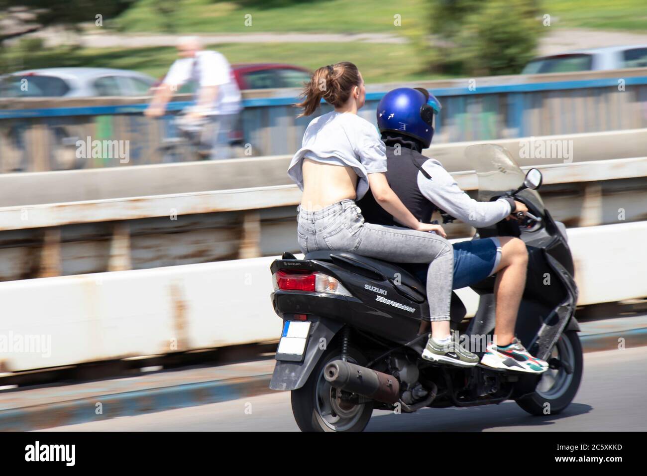 Belgrado, Serbia - 4 luglio 2020: Giovane uomo e donna senza casco in sella a uno scooter sul ponte della città Foto Stock