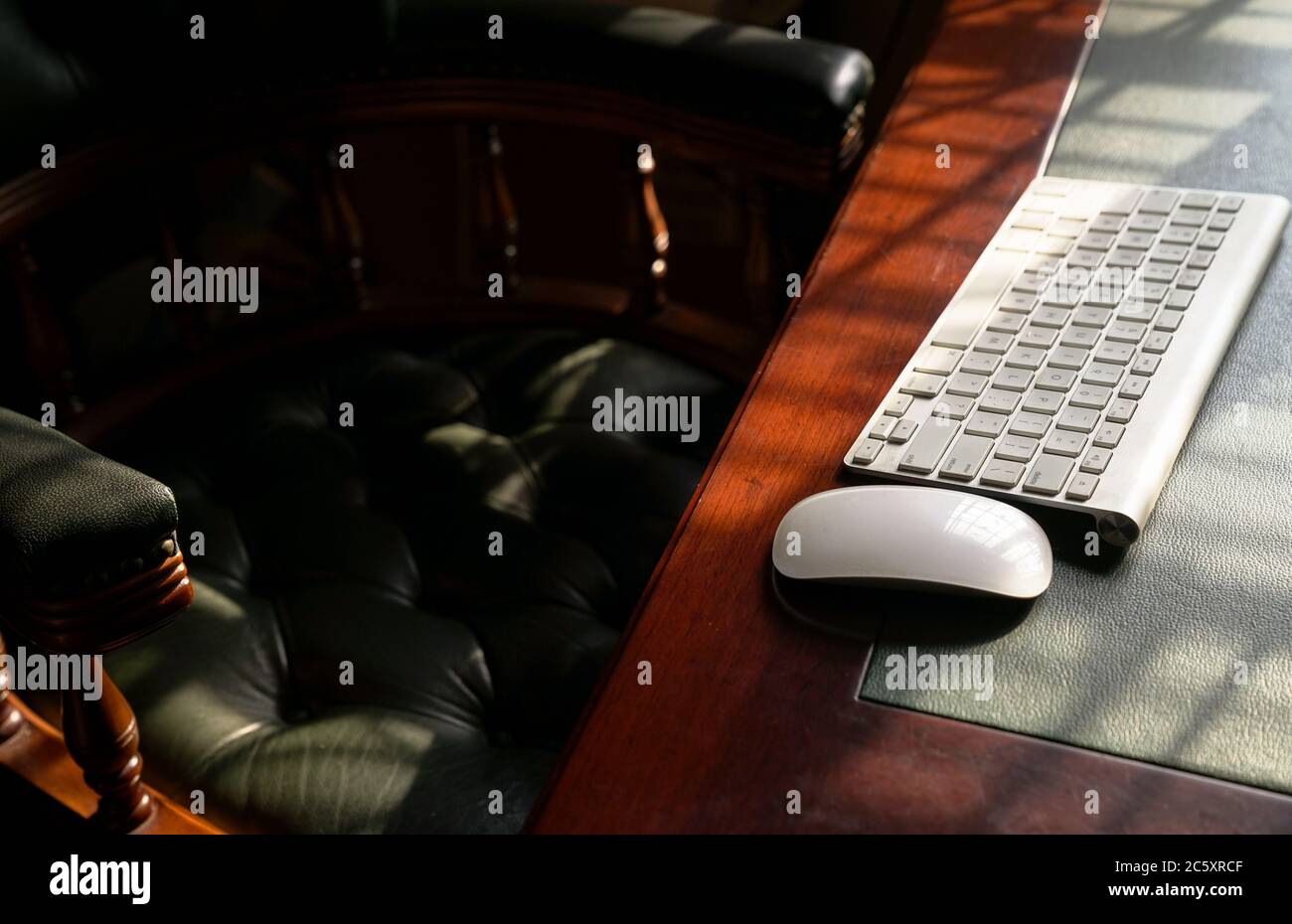 Tastiera per computer su tavolo in legno e pelle. Gioco di luce che forma linee e ombre. Spazio di copia. Foto Stock