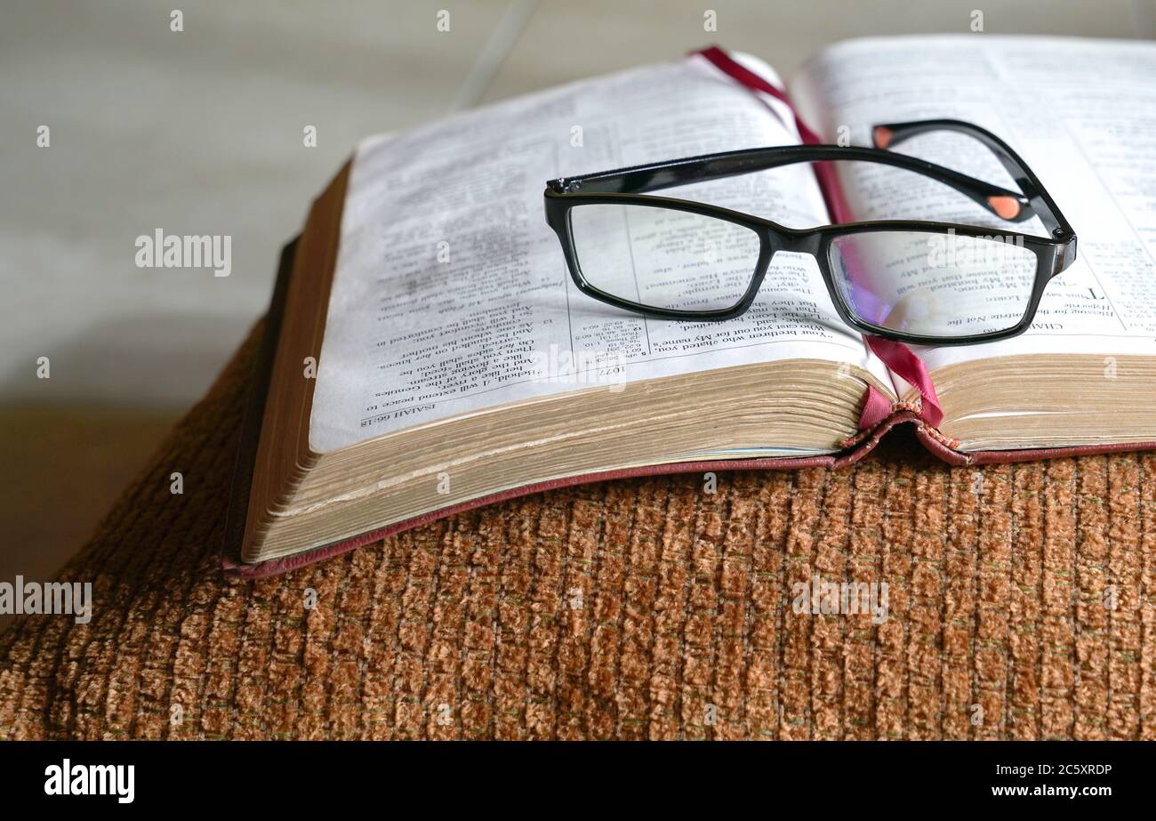 Apri la bibbia su un pilone, con gli occhiali da lettura sopra di esso. Spazio di copia. Foto Stock