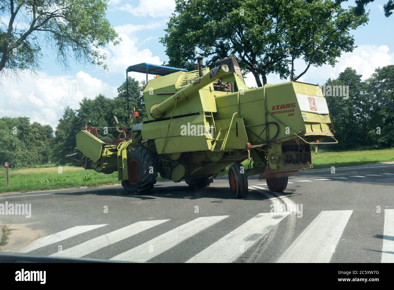 Macchina da raccolta verde sulla strada per il campo agricolo successivo. Zawady Gmina Rzeczyca Polonia Foto Stock