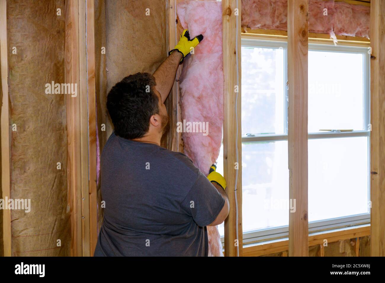 Lavoratori edili strato isolante termico sotto casa con lana di vetro morbido fuoco Foto Stock
