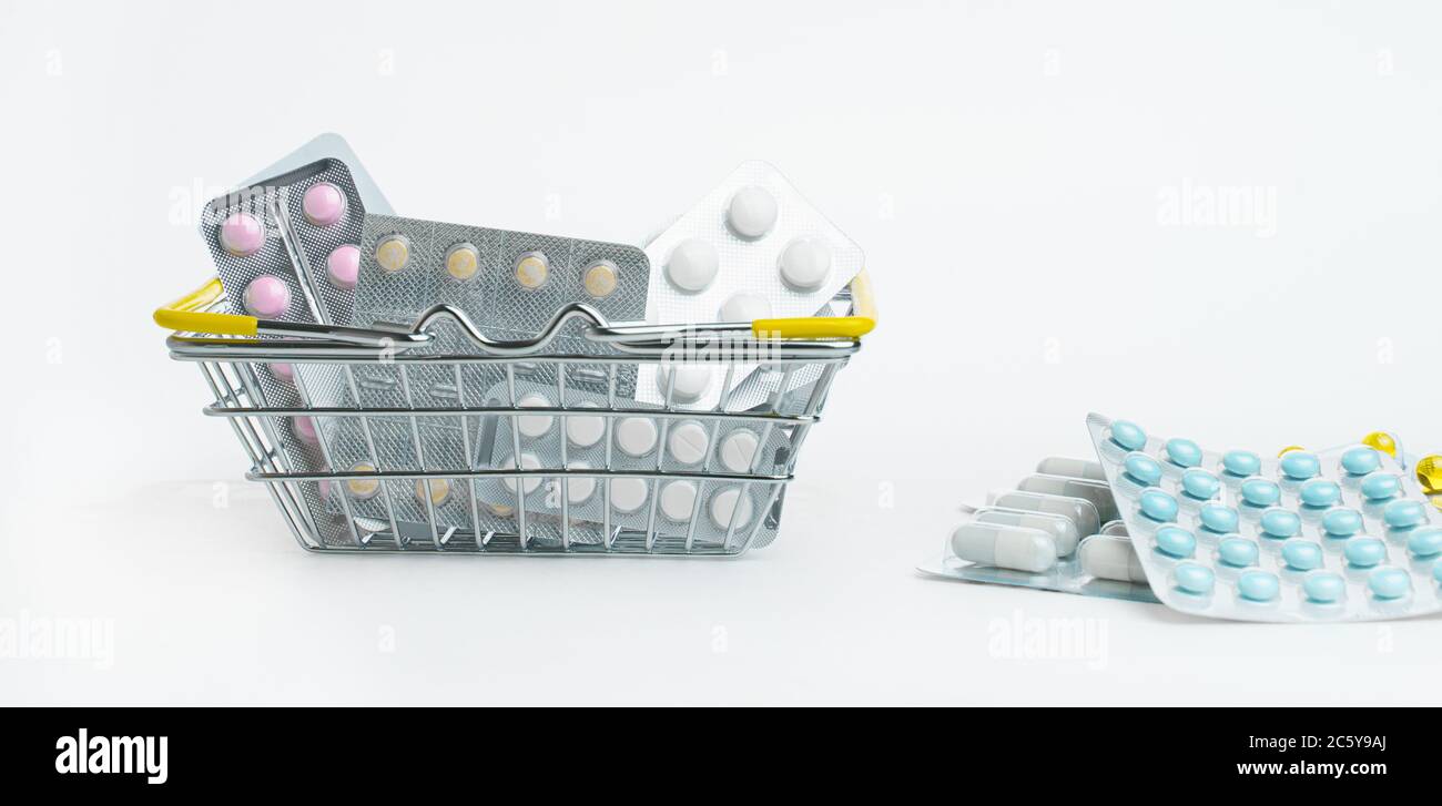 Varie pillole in blister sono in un piccolo cestino di shopping su uno sfondo bianco. Vendita di farmaci in negozi e farmacie. Salute e medicina. Foto Stock