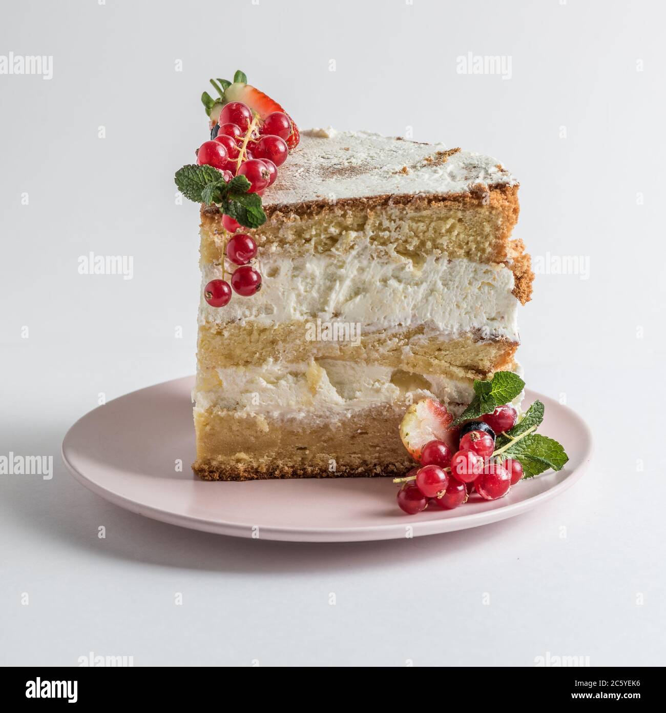 Fetta di pan di Spagna con bacche su piatto bianco su fondo bianco. Foto Stock
