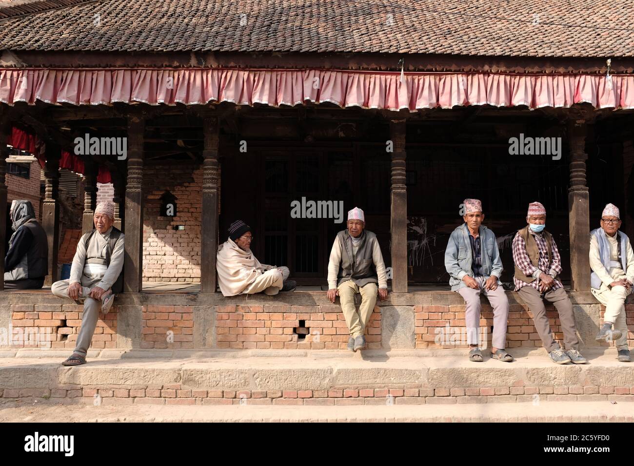 Alcuni uomini nepalesi indossano Dhaka Tobi seduti in un tempio in Bhaktapur Durbar Square, Nepal Foto Stock