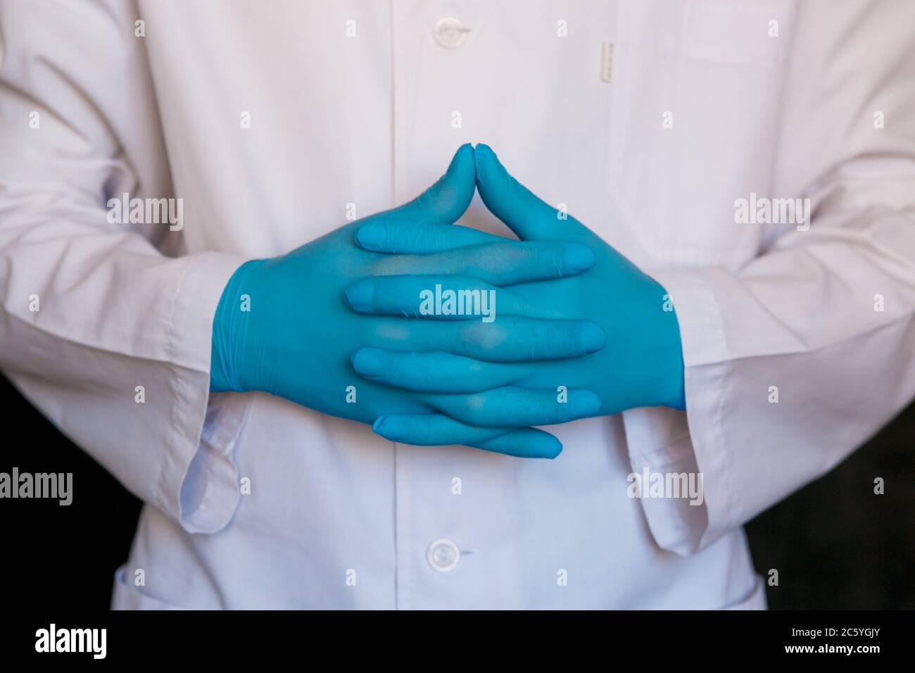 primo piano del medico. Guanti medici del chirurgo su sfondo nero. Foto Stock