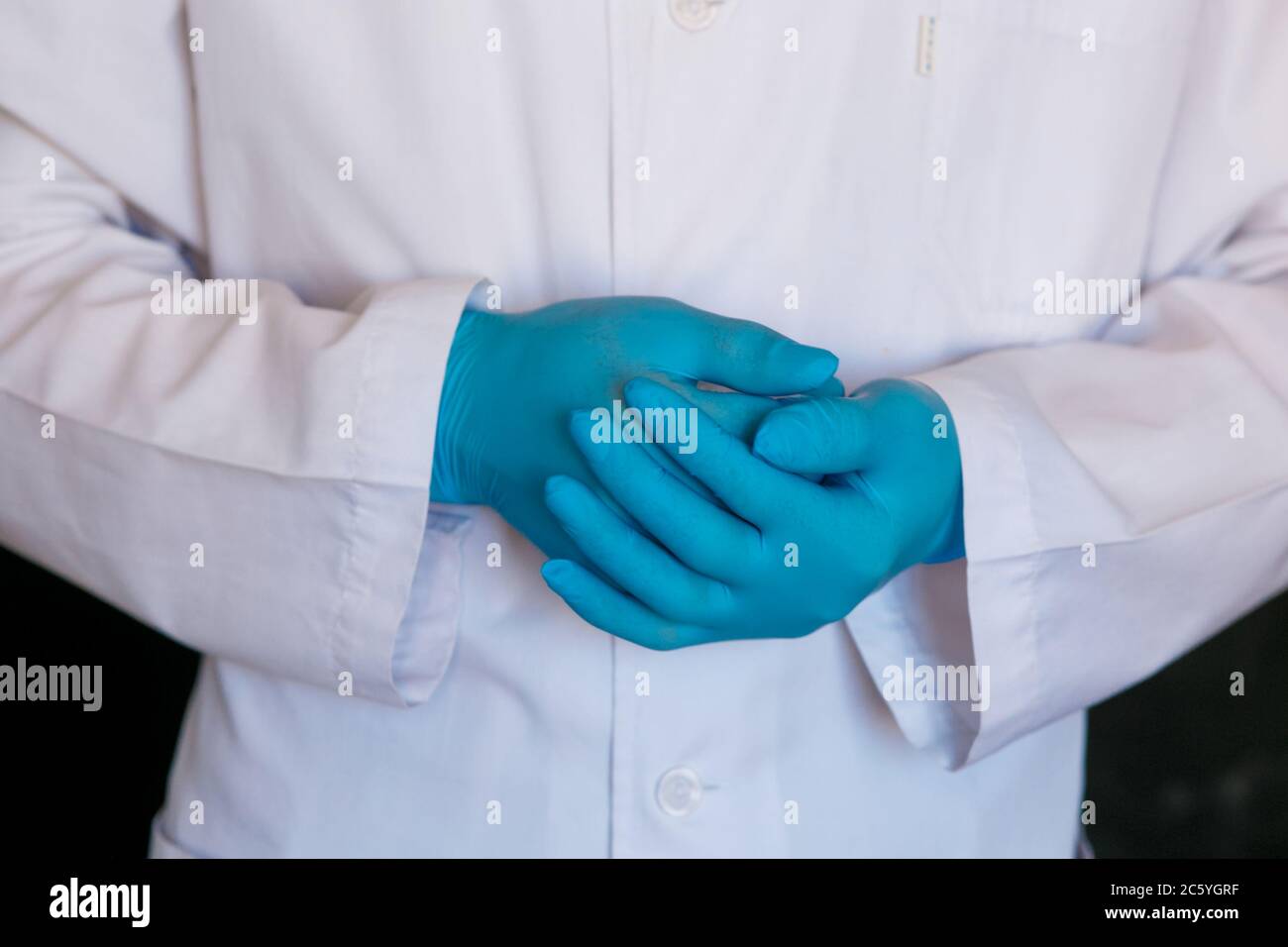 primo piano del medico. Guanti medici del chirurgo su sfondo nero. Foto Stock
