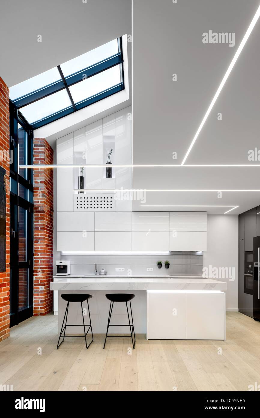 Cucina spaziosa e moderna in bianco con grandi finestre da pavimento a soffitto Foto Stock