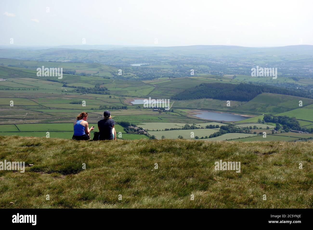 Una coppia seduto e godendo la vista dei serbatoi di Black Moss dalla cima di Pendle Hill sul sentiero Pendle Way da Barley, Lancashire, Regno Unito. Foto Stock