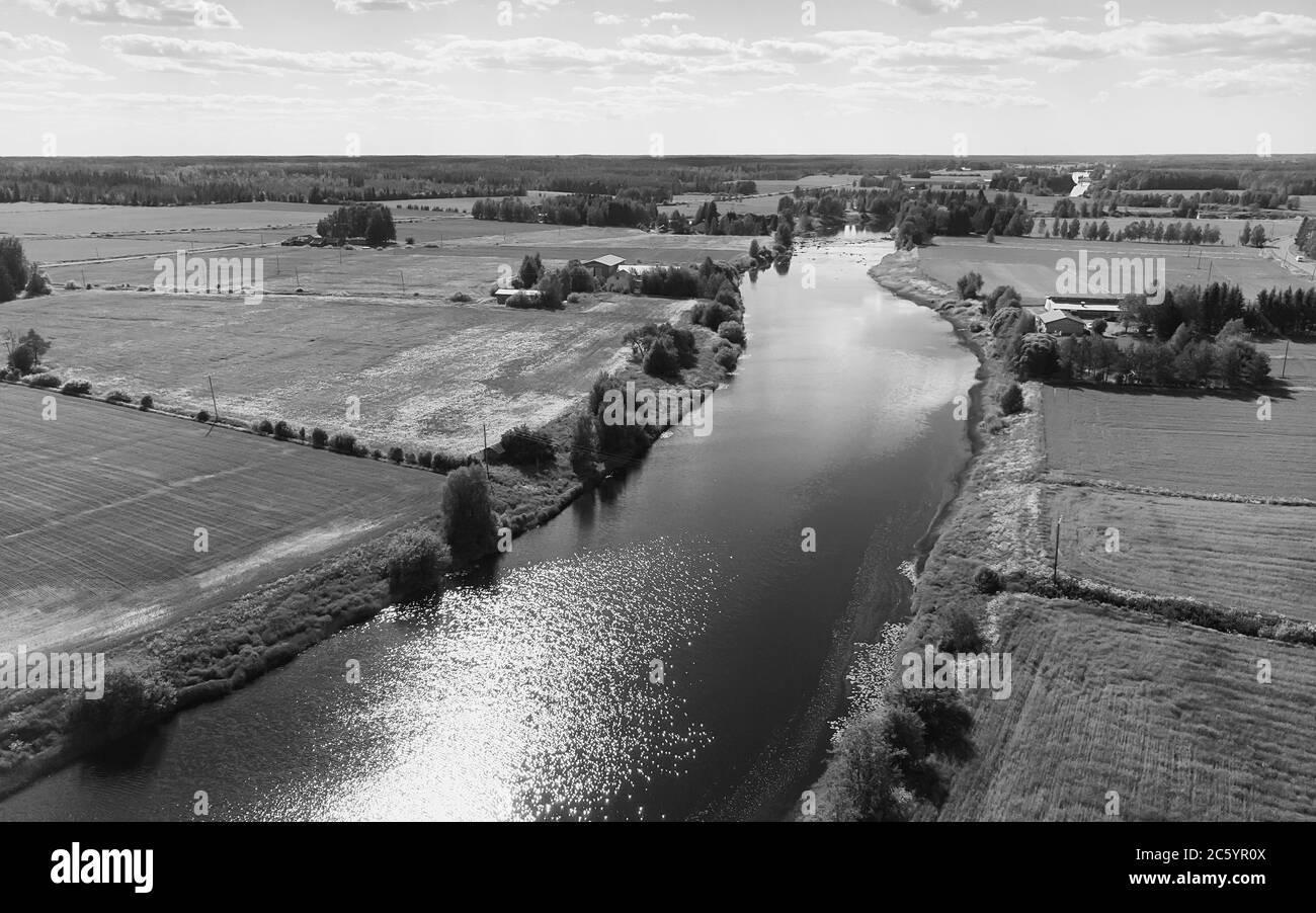 Il fiume attraversa i campi verdi della Finlandia rurale. Foto Stock