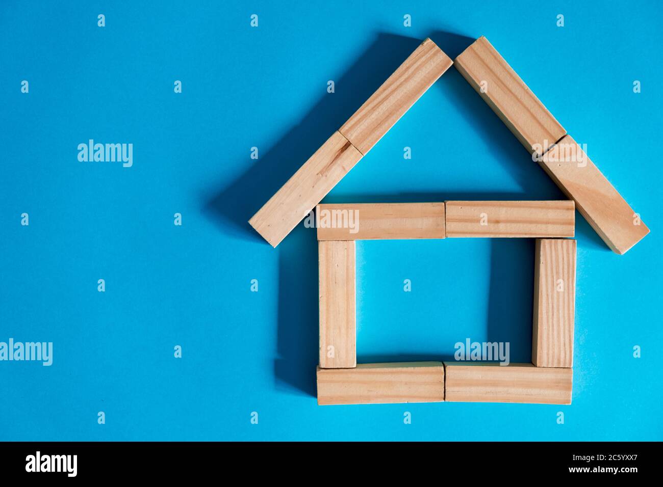 Casa di legno su sfondo blu. Prestare al pubblico. Il concetto di alloggio a prezzi accessibili e ipoteche per acquistare una casa. Foto Stock