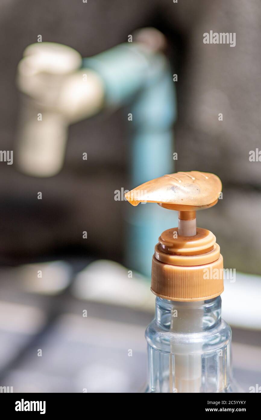 Un rubinetto e detersivo per piatti in cucina all'aperto. Un rubinetto e una bottiglia di plastica da vicino con liquido di disinfezione o sapone. Foto Stock