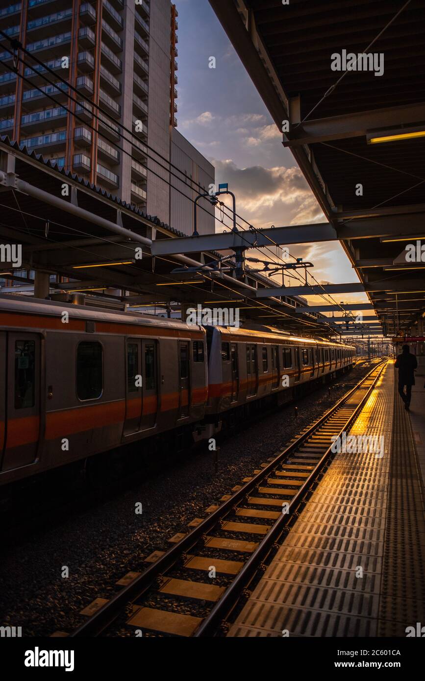 Alla fermata del treno a Tokyo, Giappone, dove il bagliore serale si illumina quando il treno arriva, Foto Stock