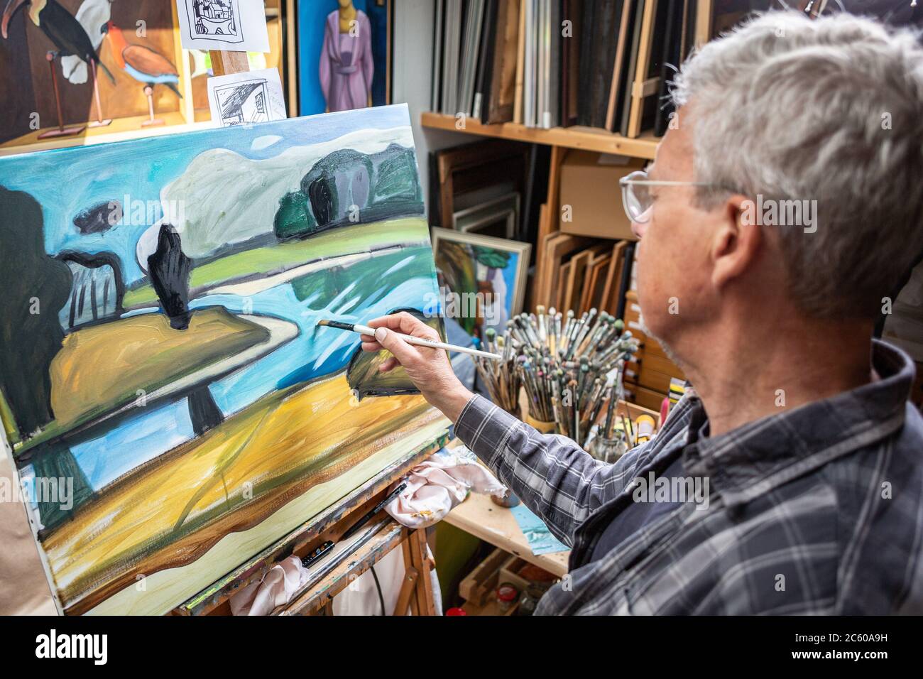Uomo anziano che dipinge un paesaggio su tela Foto Stock