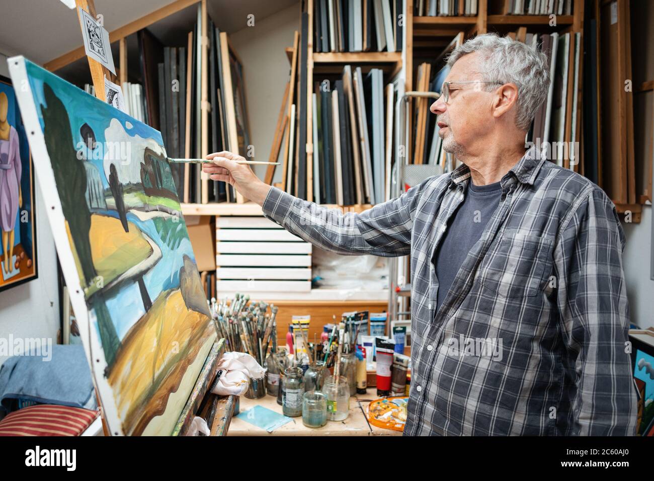 Artista senior pittura su tela nel suo studio Foto Stock