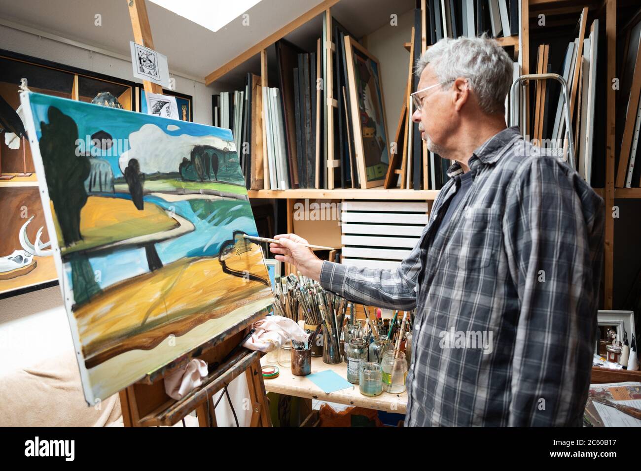 Uomo anziano nel suo studio di pittura un paesaggio Foto Stock