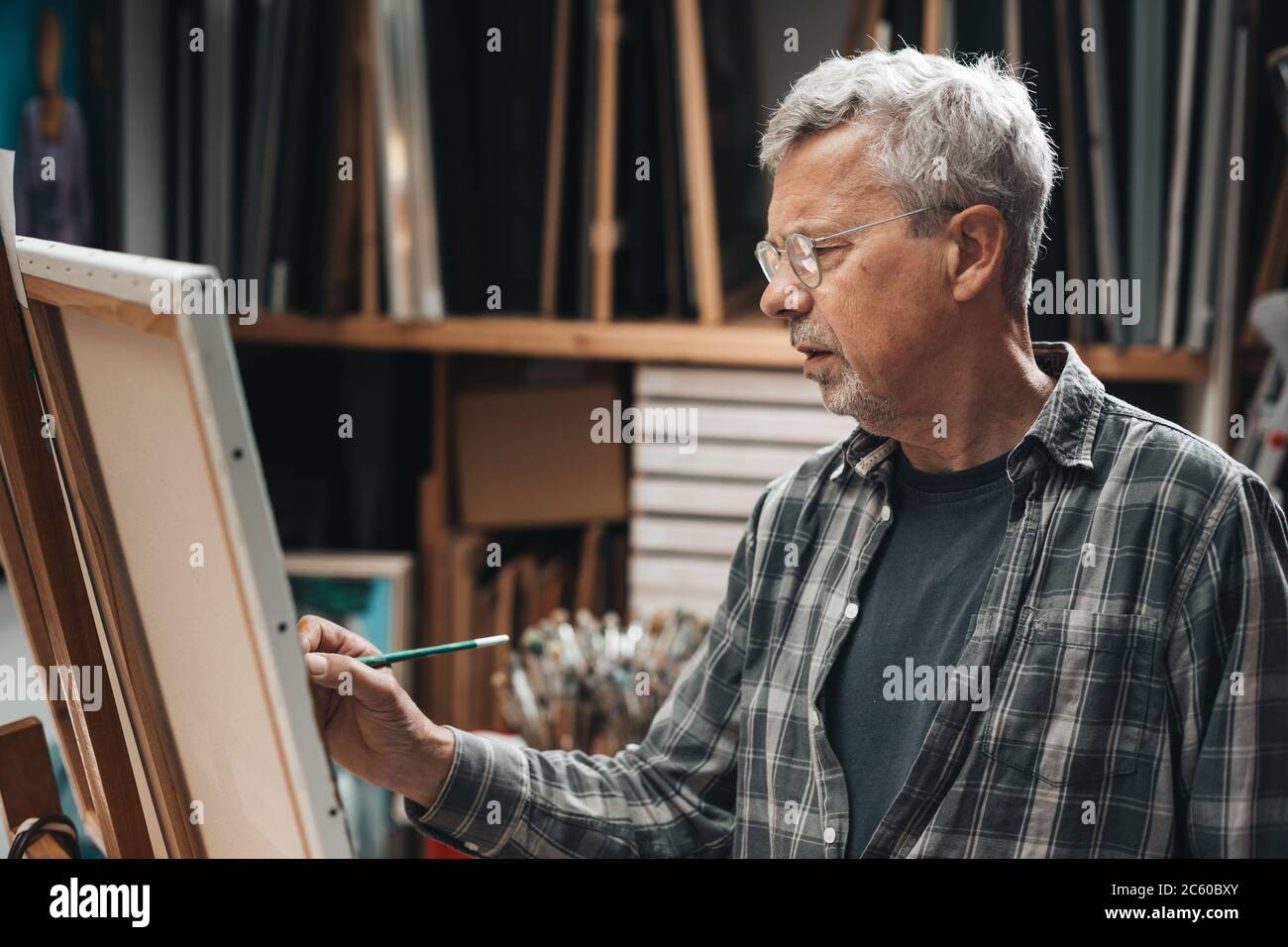 Uomo maturo pittura nel suo studio Foto Stock