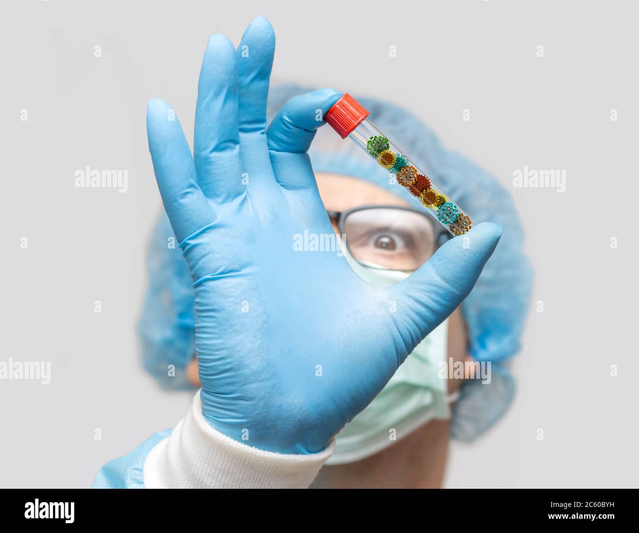 Il medico tiene la provetta con una raccolta di virus all'interno, mettere a fuoco su una mano, viso sfocato. Ricerca di un microrganismo pericoloso. Foto Stock