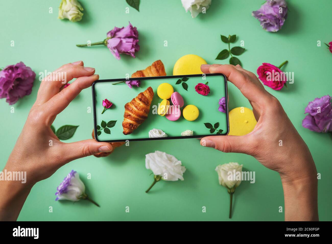 blog alimentare - blogger che scattano foto di macaron e croissant con telefono Foto Stock