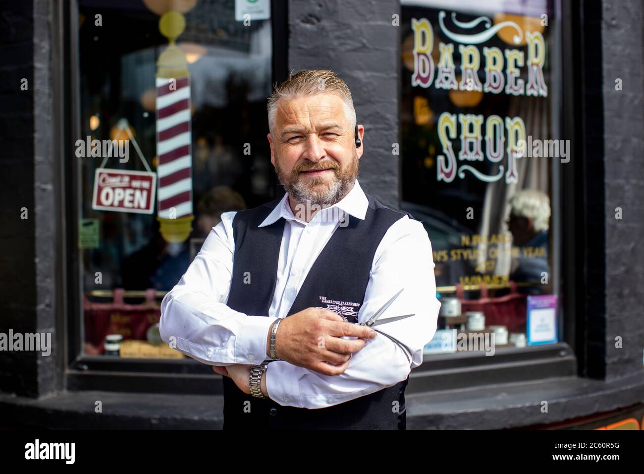 Sean Lawlor, coproprietario di Cambridge Barbershop sulla Lisburn Road di Belfast, si erge fuori dal suo negozio mentre i parrucchieri e i saloni di bellezza riaprono in Irlanda del Nord, parte dell'ultima misura per alleviare le restrizioni del coronavirus. Foto Stock