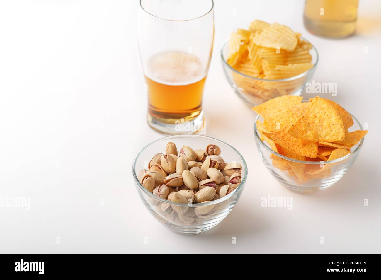 Spuntino con birra. Lager brillante in vetro, pistacchi, nachos e patatine Foto Stock