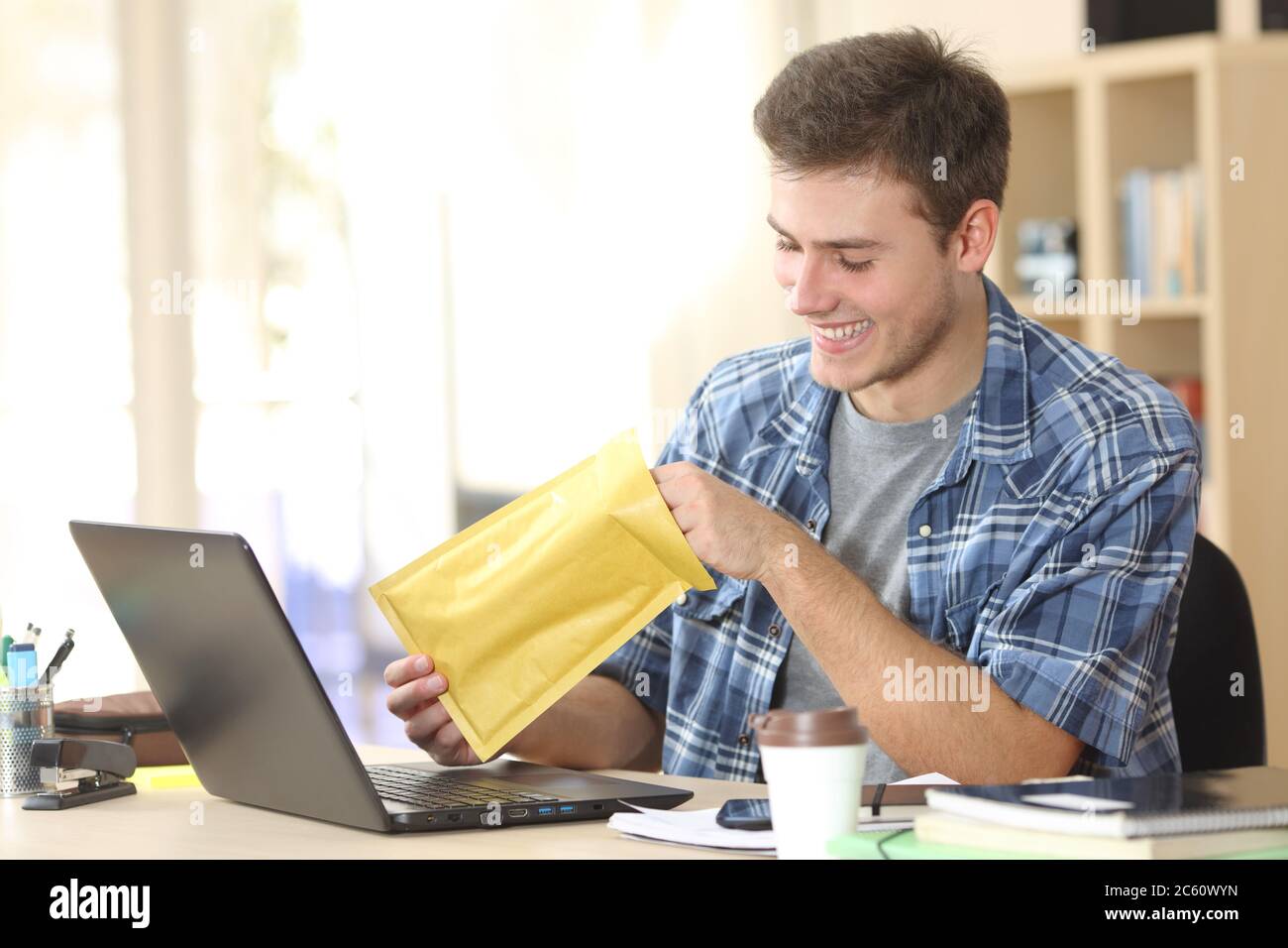 Felice uomo imprenditore apre busta seduta su una scrivania in ufficio Foto Stock