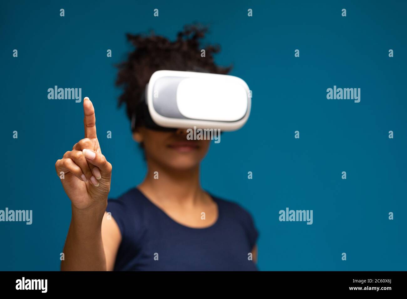 Donna afro-americana che usa il visore VR, toccando il touchscreen invisibile Foto Stock